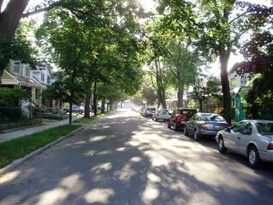 Looking down a street lined with cars in the Danforth village in Toronto
