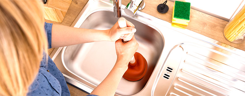 woman that needs her clogged drain repaired, attempting to fix blocked drain with a plunger,